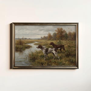 May include: A framed painting depicts two hunting dogs in a marshy landscape. One dog is brown and white, the other is solid brown. The artwork features a river, tall grass, and trees under a cloudy sky.