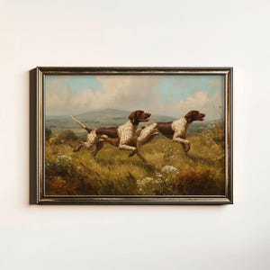 May include: An antique framed painting depicts two brown and white dogs running through a field of tall grass and wildflowers. The dogs are in mid-stride, with a landscape of rolling hills and a cloudy sky in the background.