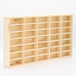 May include: A rectangular light-colored wooden display shelf featuring a grid of thirty-two individual compartments arranged in four horizontal rows and eight vertical columns, showcasing a natural wood grain texture and visible joinery details.