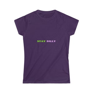 Puede incluir: Una camiseta morada con las palabras "STAY SILLY" impresas en verde y morado en el pecho. La camiseta tiene mangas cortas y cuello redondo. La tela parece suave y cómoda.