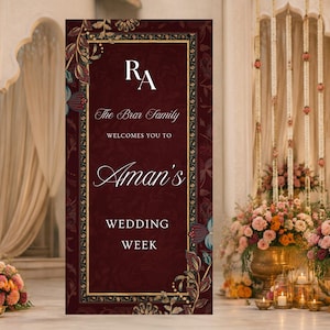 May include: A vertical rectangular welcome sign in deep burgundy with a gold border and floral accents. The text reads: RA, The Brar Family, WELCOMES YOU TO, Aman's, WEDDING WEEK. The design features white serif and script typography on a dark background.