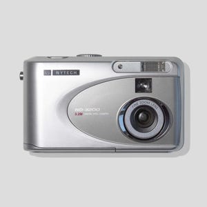 May include: A silver Nytech ND-3200 digital camera featuring a 3.2M resolution lens. The front of the device displays the brand name Nytech, the model number ND-3200, and the text 3.2M Digital Still Camera. It includes a built-in flash and lens.