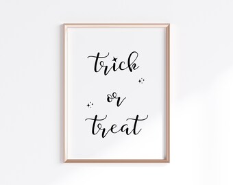 Puede incluir: Impresión enmarcada con la frase "trick or treat" en escritura negra. El texto está centrado sobre un fondo blanco, con pequeños detalles de estrellas. El marco es de color dorado claro.