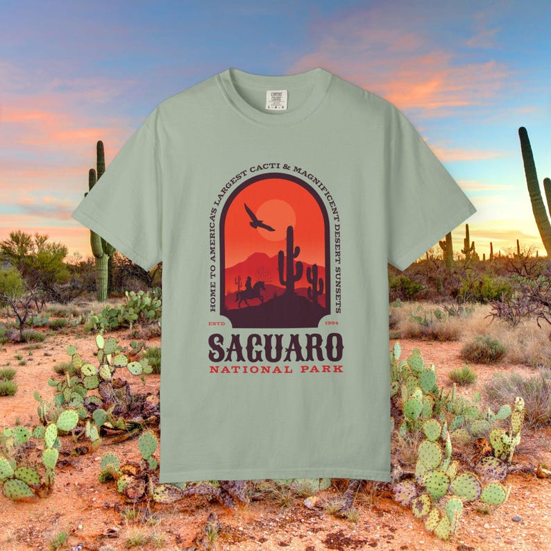 Comfort Colors Tshirt with front & Back graphic featuring a desert scene with cactus and cowboy. The text reads Saguaro National Park. Home to Americas Largest Cacti and Magnificent Desert Sunsets.