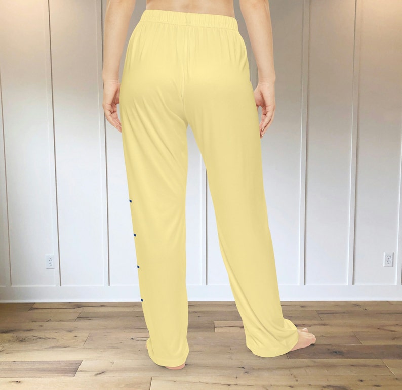 A pair of light yellow pajama pants with a graphic print down the leg that resembles the hatch marks on a stick of butter. the front left of the pants also has a graphic that reads "SALTED BUTTER net wt 4 oz"