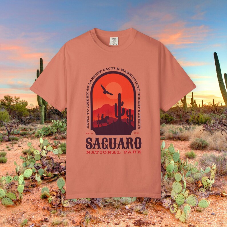 Comfort Colors Tshirt with front & Back graphic featuring a desert scene with cactus and cowboy. The text reads Saguaro National Park. Home to Americas Largest Cacti and Magnificent Desert Sunsets.