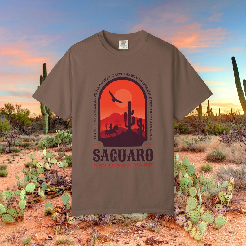 Comfort Colors Tshirt with front & Back graphic featuring a desert scene with cactus and cowboy. The text reads Saguaro National Park. Home to Americas Largest Cacti and Magnificent Desert Sunsets.