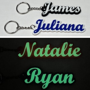 May include: Four personalized keychains with names "James", "Juliana", "Natalie", and "Ryan". The first two keychains are white with blue lettering, and the last two are green and glow in the dark.