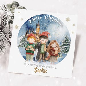 Könnte beinhalten: Weihnachtskarte mit einer Illustration von drei Kindern in Winterkleidung vor einer verschneiten Burg. Der Text "Merry Christmas" und "To a special granddaughter Sophie" ist enthalten.