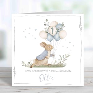 Peut inclure: Carte de vœux carrée avec une illustration à l'aquarelle d'un lapin tenant des ballons. Les ballons sont crème et bleus, avec le chiffre 1 sur l'un d'eux. Le texte dit "Happy 1st Birthday to a Special Grandson Ollie."