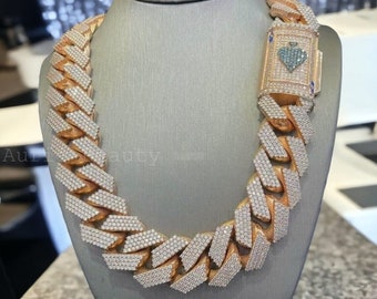 May include: A gold-toned chain necklace with a large link design, encrusted with numerous small, sparkling stones. The clasp features a heart-shaped design with blue and white accents. The necklace is displayed on a gray mannequin.