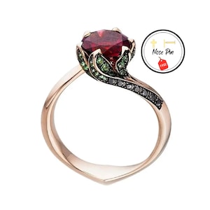 May include: A rose gold ring featuring a red gemstone surrounded by green stones. The band is twisted and set with black diamonds.
