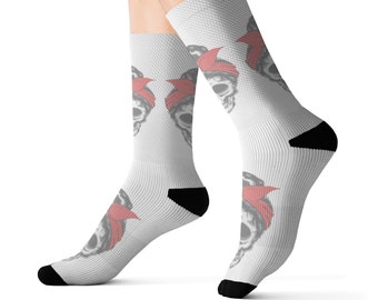 Puede incluir: Un par de calcetines blancos de caña media con un estampado gráfico repetitivo de una calavera con un pañuelo rojo. Los calcetines tienen talones y punteras de color negro sólido, con una textura acanalada en todo el tejido.