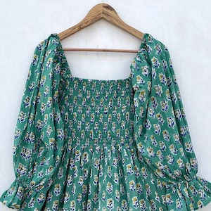 May include: A green floral print dress with a square neckline and puffed sleeves. The dress has a smocked bodice and a flowing skirt.