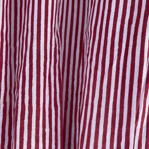 May include: Red and white striped fabric with a textured pattern. The fabric is folded and has a slight sheen.