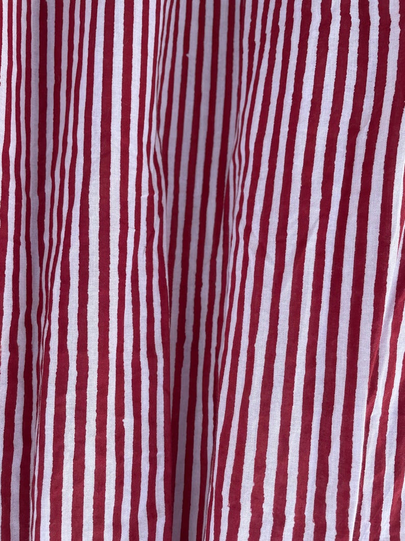 May include: Red and white striped fabric with a textured pattern. The fabric is folded and has a slight sheen.
