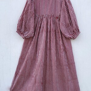 May include: A red and white striped midi dress with a high neck and puffed sleeves. The dress has a gathered waist and a flowy skirt.