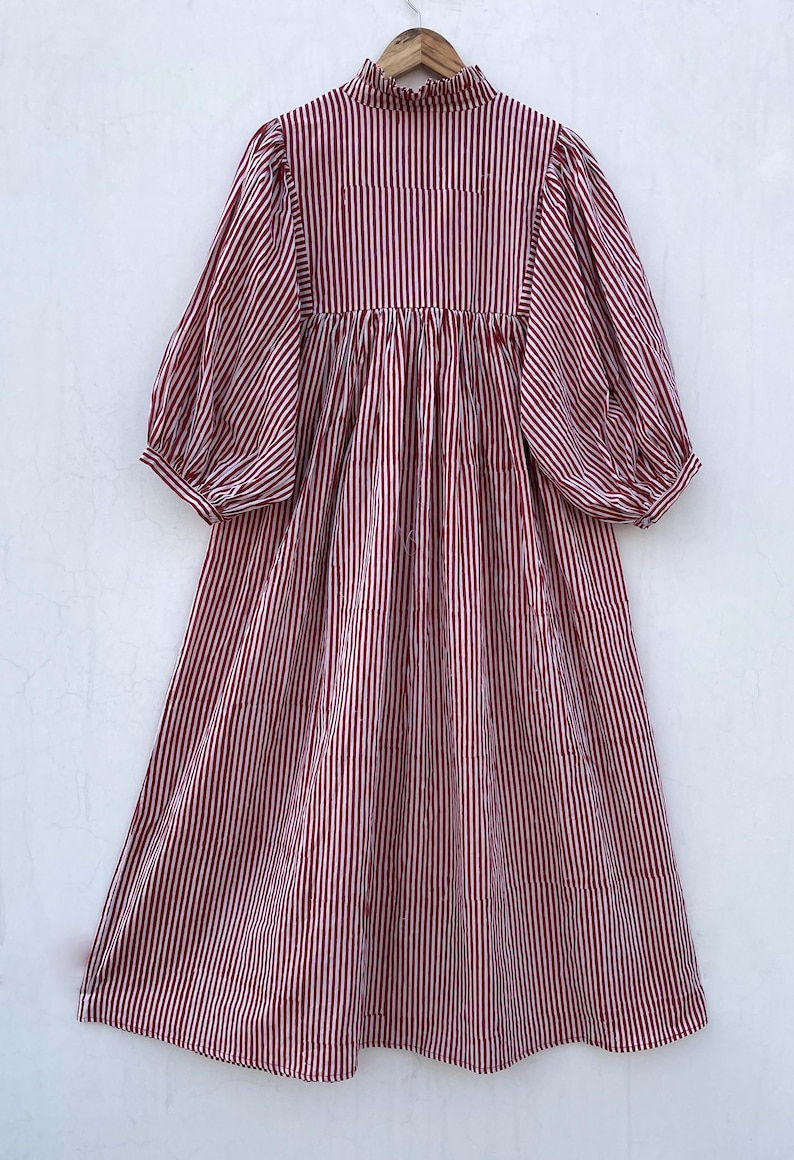 May include: A red and white striped midi dress with a high neck and puffed sleeves. The dress has a gathered waist and a flowy skirt.