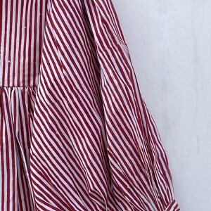 May include: A red and white striped dress with a gathered skirt and puffed sleeves.
