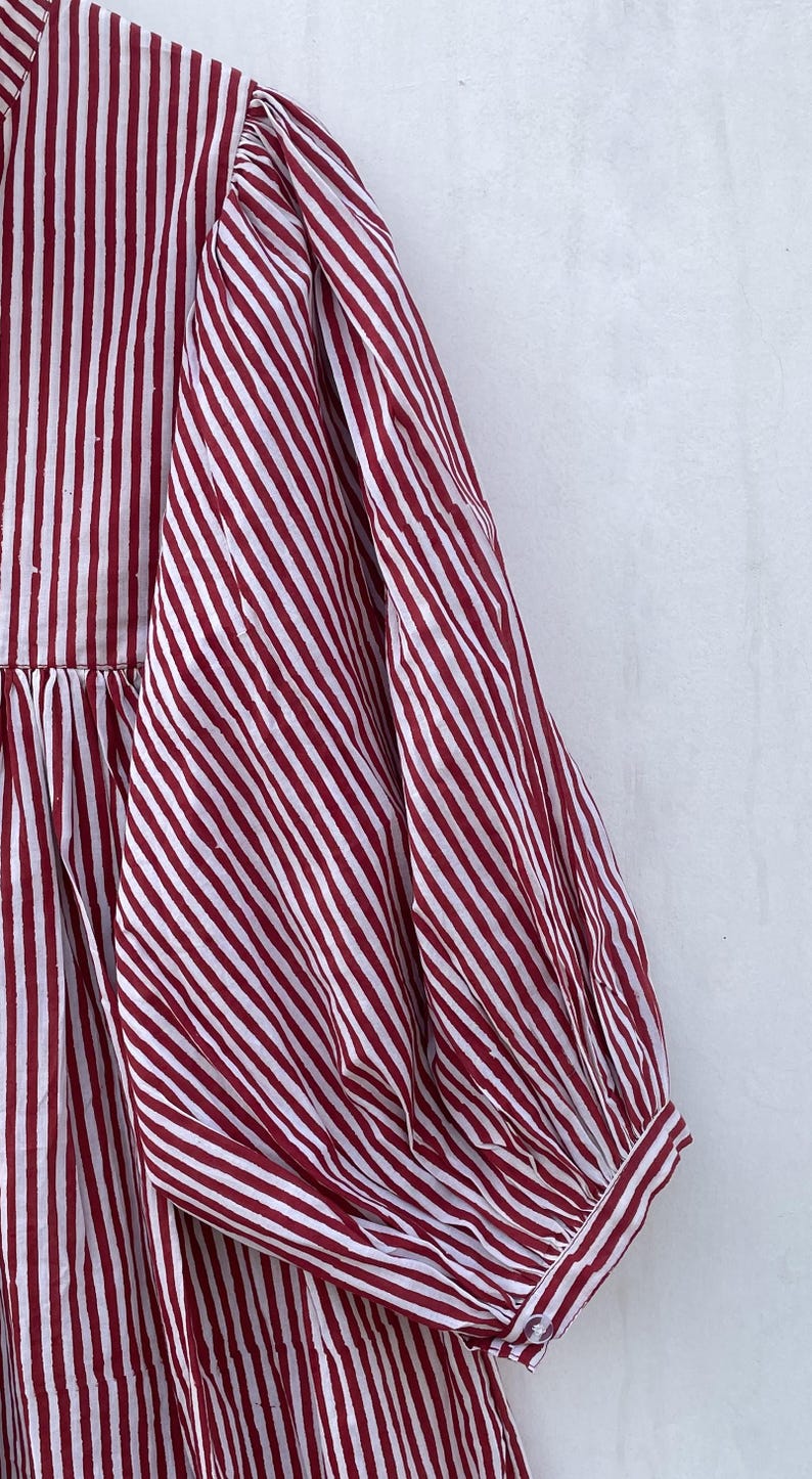 May include: A red and white striped dress with a gathered skirt and puffed sleeves.