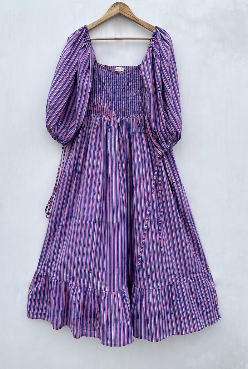 May include: A purple and pink striped midi dress with a square neckline, puffed sleeves, and a smocked bodice. The dress has a tiered skirt and ties at the waist.