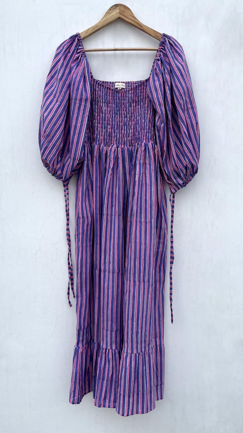 May include: A purple and pink striped midi dress with puffed sleeves and a smocked bodice. The dress has a square neckline and a tiered skirt.