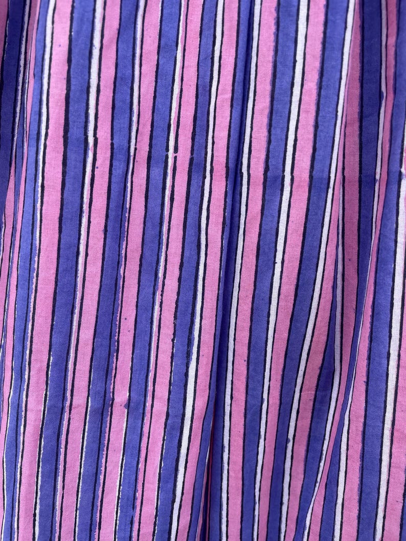 May include: Close-up of a fabric with vertical stripes in pink, blue, and white.