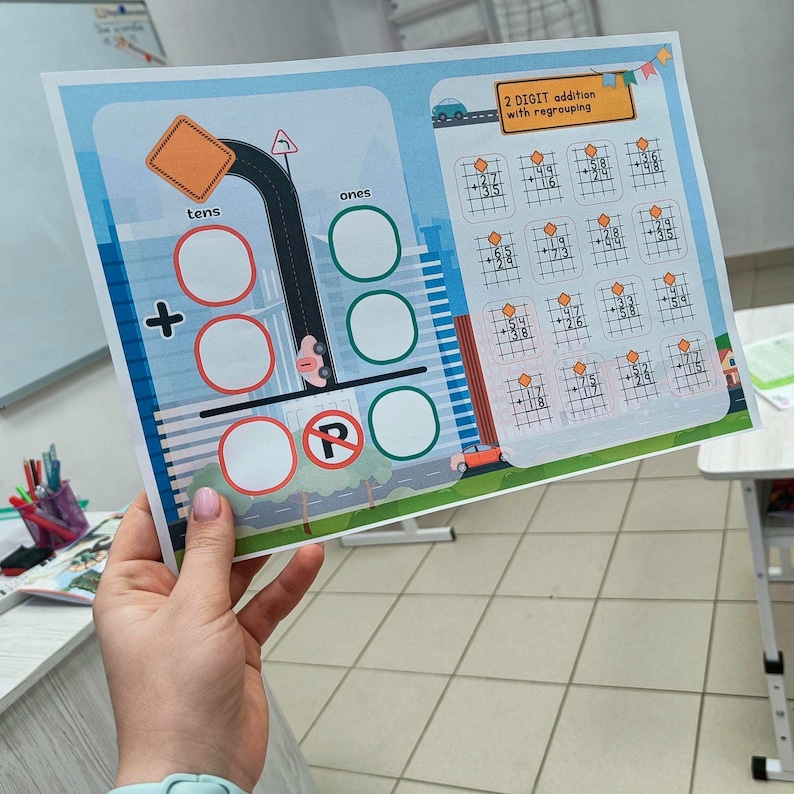 May include: A colourful educational worksheet for 2-digit addition with regrouping. The worksheet features a road design with a parking sign, a plus sign, and spaces for tens and ones. The top right corner has addition problems.