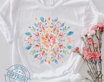 Könnte beinhalten: Ein weißes Kurzarm-T-Shirt mit einem zentralen, kreisförmigen Aquarell-Design aus bunten Blättern und Blütenblättern in Blau-, Orange-, Rosa- und Gelbtönen. Das T-Shirt hat einen Rundhalsausschnitt und eine Standardpassform aus weichem Stoff.