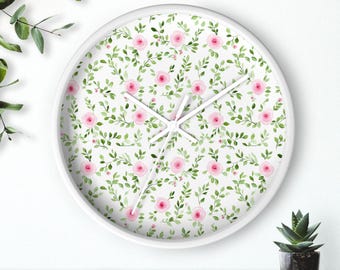 May include: White round clock with a floral pattern featuring pink roses and green leaves on the face.