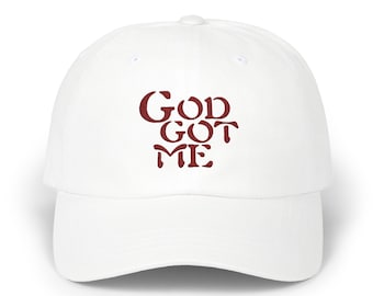 May include: A white baseball cap featuring the burgundy text "God Got Me". The cap has a curved peak and a classic six-panel design. Suitable for casual wear, it's a versatile accessory.