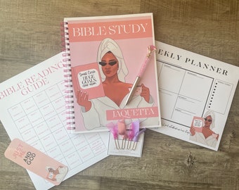 May include: A pink and white Bible study set featuring a spiral-bound notebook, pen, weekly planner, bookmark, and Bible reading guide. The notebook cover has the text "BIBLE STUDY" and an illustration of a woman. The pen has a diamond-shaped top.
