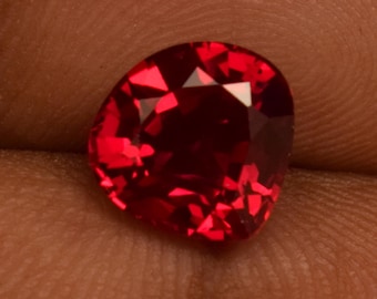 Puede incluir: Una piedra preciosa de color rojo intenso con un corte facetado. La piedra preciosa tiene forma de corazón y tiene un alto pulido.