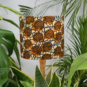 May include: A lampshade with a white background and a pattern of orange and brown circles. The lampshade is made of fabric and has a wooden base.
