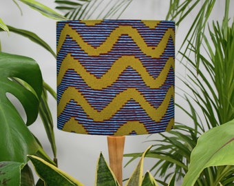 May include: A lampshade with a geometric pattern in shades of mustard yellow, blue, and brown. The pattern is a series of zigzags.