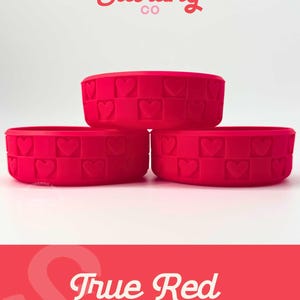May include: Three true red silicone bowls stacked. Each bowl features a heart pattern around the rim. The text "Sweet Starling Co" is at the top, and "True Red Pixie" is at the bottom.