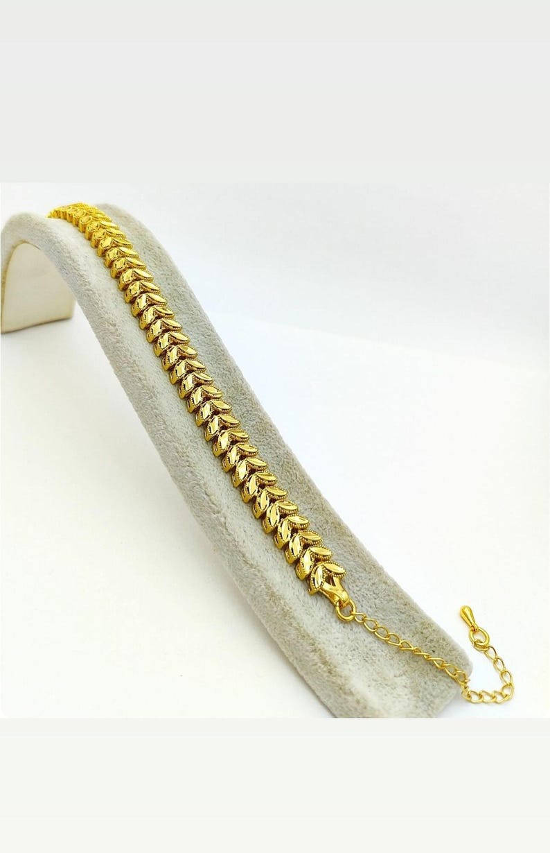 May include: A gold bracelet with a leaf-shaped chain design. The bracelet has a lobster clasp closure.