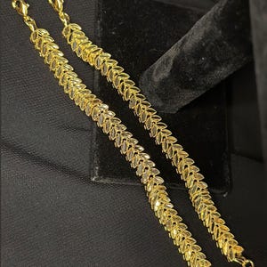 May include: Two gold leaf-shaped chain bracelets with lobster claw clasps.