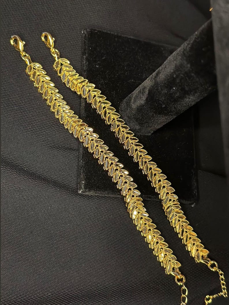 May include: Two gold leaf-shaped chain bracelets with lobster claw clasps.