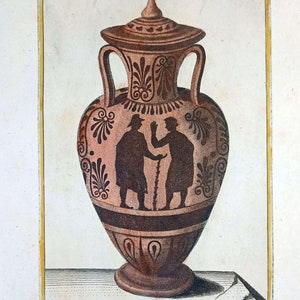 Può includere: Un vaso in ceramica marrone e nero con un coperchio, decorato con una silhouette nera e bianca di due figure. Il vaso è su un piedistallo bianco e il testo "In Museo Vaticano" è scritto sotto il vaso.
