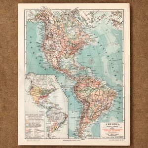 May include: A vintage printed map of the Americas featuring North and South America in shades of peach and green. The map includes a smaller inset map of the continents, detailed geographical labels, and the text AMERIKA in the bottom right corner.
