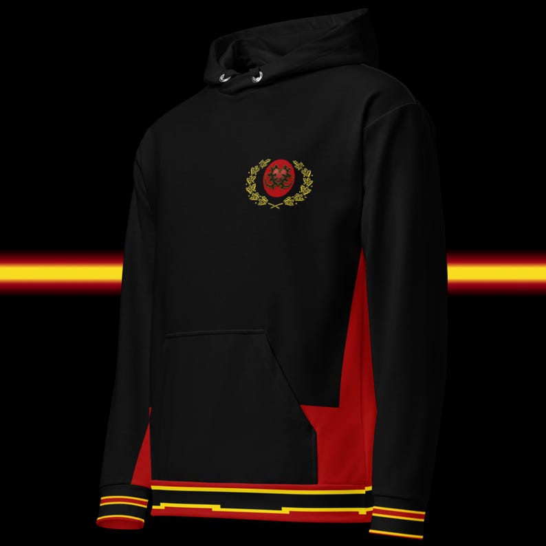 May include: Black hoodie with red side panels and a front pocket. The hoodie features a crest design on the chest and stripes on the cuffs and hem. The design includes gold and red accents.