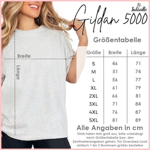 以下が含まれることがあります： ライトグレーのGildan 5000 Tシャツ。画像には、センチメートル単位のサイズチャートと「Alle Angaben in cm」のテキストが含まれています。シャツがモデルになっています。