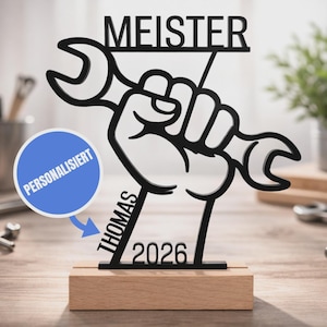 Könnte beinhalten: Ein schwarzes Ausschnitt-Schild mit einer Faust, die einen Schraubenschlüssel hält, auf einem rechteckigen Holzsockel. Das Wort MEISTER steht oben, der Name THOMAS und das Jahr 2026 sind integriert. Ein blauer Kreis zeigt den Text PERSONALISIERT.