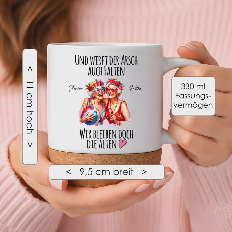 May include: A white ceramic mug with a cork base, featuring a graphic of two older individuals with floral crowns and sunglasses, holding a beach ball. The text reads: Und wirft der Arsch auch Falten, wir bleiben doch die Alten. It is 11 cm high, 9.5 cm wide, and holds 330 ml.