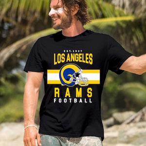May include: Black t-shirt with a yellow and white stripe, a blue and white football helmet, and the text "EST. 1937 LOS ANGELES RAMS FOOTBALL".