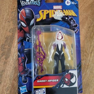 K&ouml;nnte beinhalten: Eine Ghost-Spider-Actionfigur in einer Kunststoffverpackung. Die Figur ist schwarz, wei&szlig; und lila, mit passendem Zubeh&ouml;r. Die Verpackung zeigt das Marvel Spider-Man-Logo und den Text "Venom Versus" und "Epic World of Action".