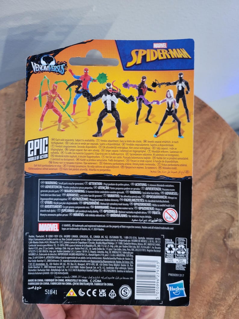 K&ouml;nnte beinhalten: Verpackung f&uuml;r Marvel Spider-Man Actionfiguren, mit verschiedenen Charakteren wie Spider-Man und Venom. Die Verpackung ist &uuml;berwiegend schwarz, blau und gelb, mit den Texten "VENOMVERSUS" und "EPIC WORLD OF ACTION".