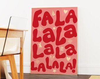 May include: A rectangular poster in a thin gold frame featuring a pink background with the red text FA LA LALA LA LA LALALA! interspersed with small cream-colored icons including a Christmas tree, snowflakes, a bell, a gift, and a reindeer.