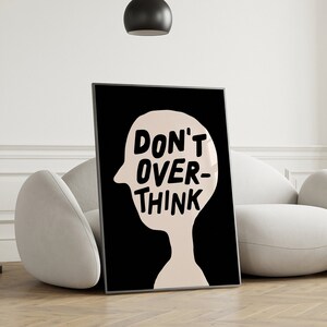 May include: Black and white poster with a silhouette of a head and the text "DON'T OVER-THINK" in bold, black letters.